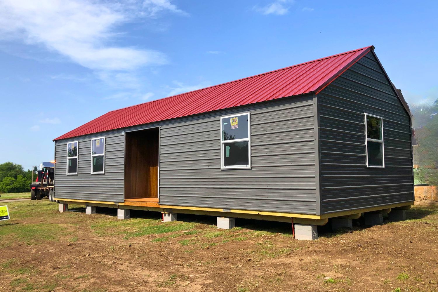 Gray shed with red roof on concrete block foundation