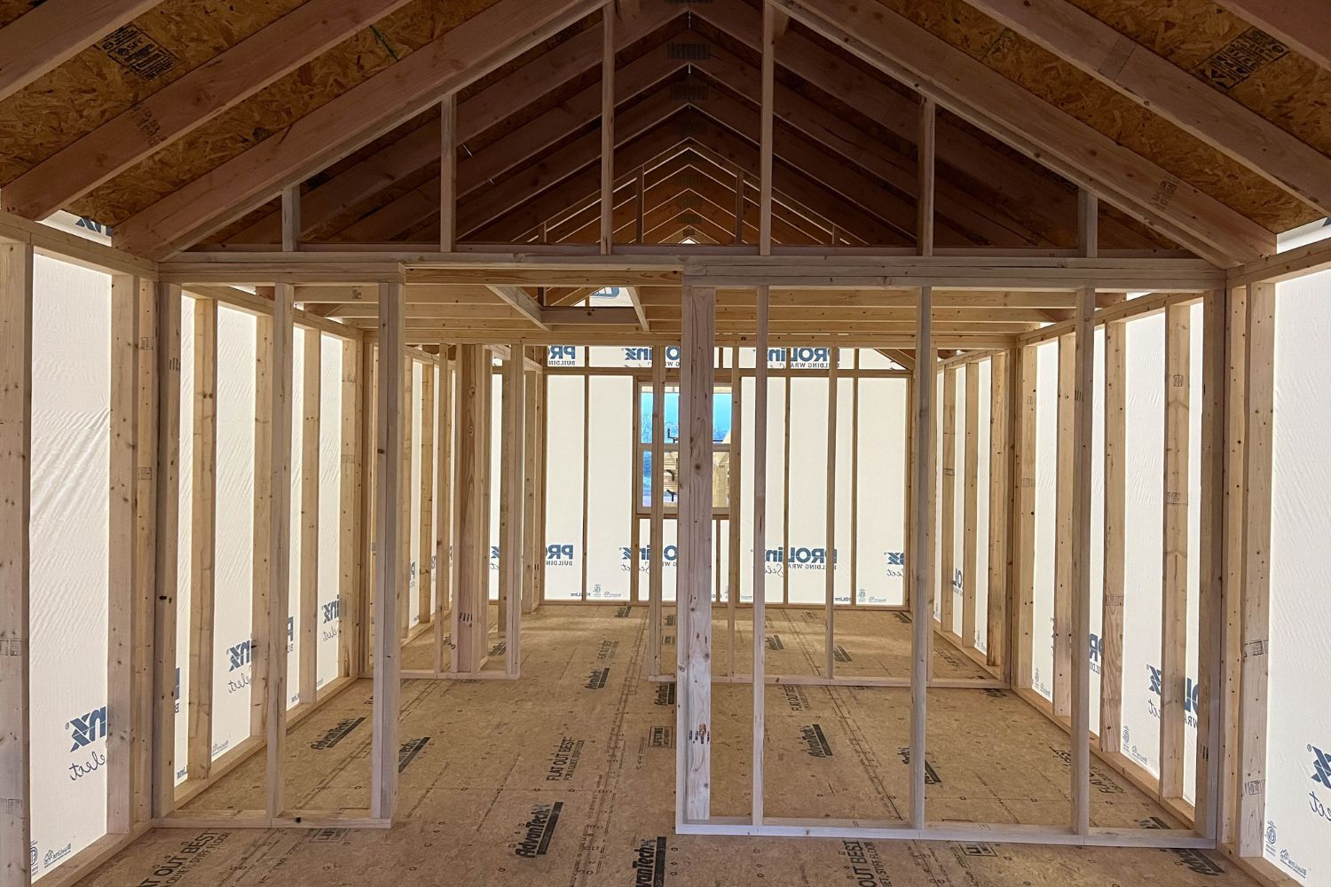 Inside unfinished log cabin shell with view of rafters and wall supports